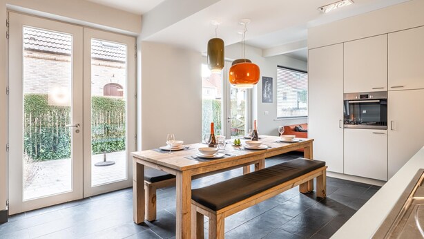 Une cuisine moderne avec une table, un banc et des luminaires suspendus en bois.