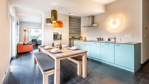 Une cuisine moderne dotée d’un îlot central, de meubles de couleur bleu clair et d’un coin repas avec une table et des bancs en bois.