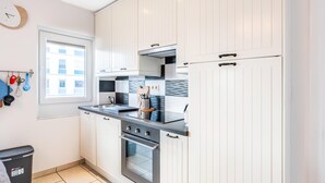 Una cocina moderna con muebles blancos, un horno de acero inoxidable y una encimera negra.