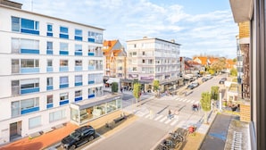 Vista de la calle con edificios modernos, un paso de peatones y coches estacionados.