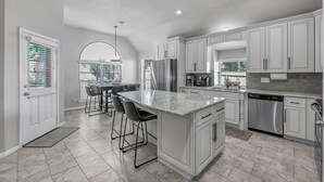Una cocina moderna con armarios blancos, electrodomésticos de acero inoxidable y encimera de mármol.