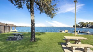 Zona verde con mesas de picnic y un embarcadero que se adentra en el agua.