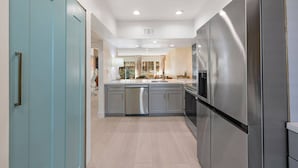 A modern kitchen with stainless steel appliances, a central island, and a view into the dining area. - Gorgeous Iconic Villa Alejo Condo, One Block from Downtown (Palm Springs)