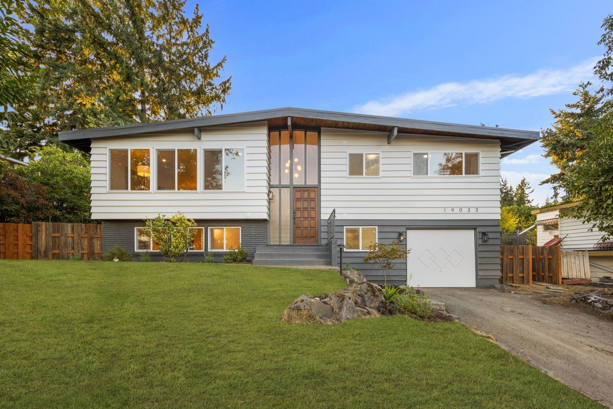 Une maison à deux étages avec un garage, une pelouse bien entretenue et une clôture en bois.