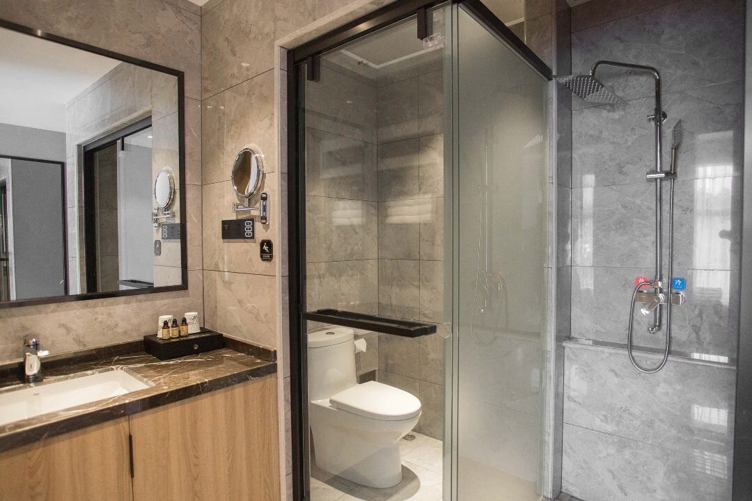 A modern bathroom with a glass-enclosed shower, a toilet, and a vanity with a mirror and sink.