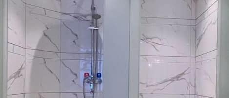 A bathroom with a shower, toilet, and marble walls.