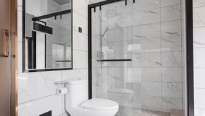 Une salle de bain moderne avec des toilettes, une douche à parois de verre et un mur recouvert de carreaux de marbre.