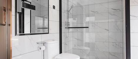 A modern bathroom with a toilet, a glass shower enclosure, and a marble-tiled wall.