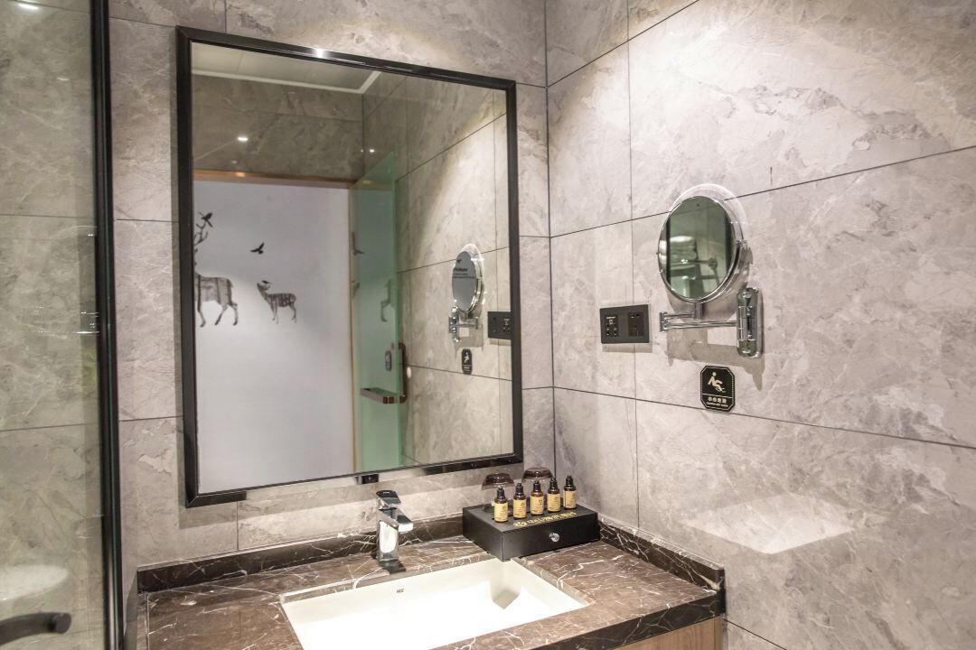A bathroom with a large mirror, a sink, and a vanity with toiletries.