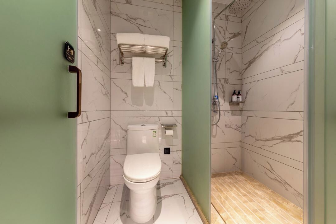 A modern bathroom with a toilet, a towel rack, and a shower area.