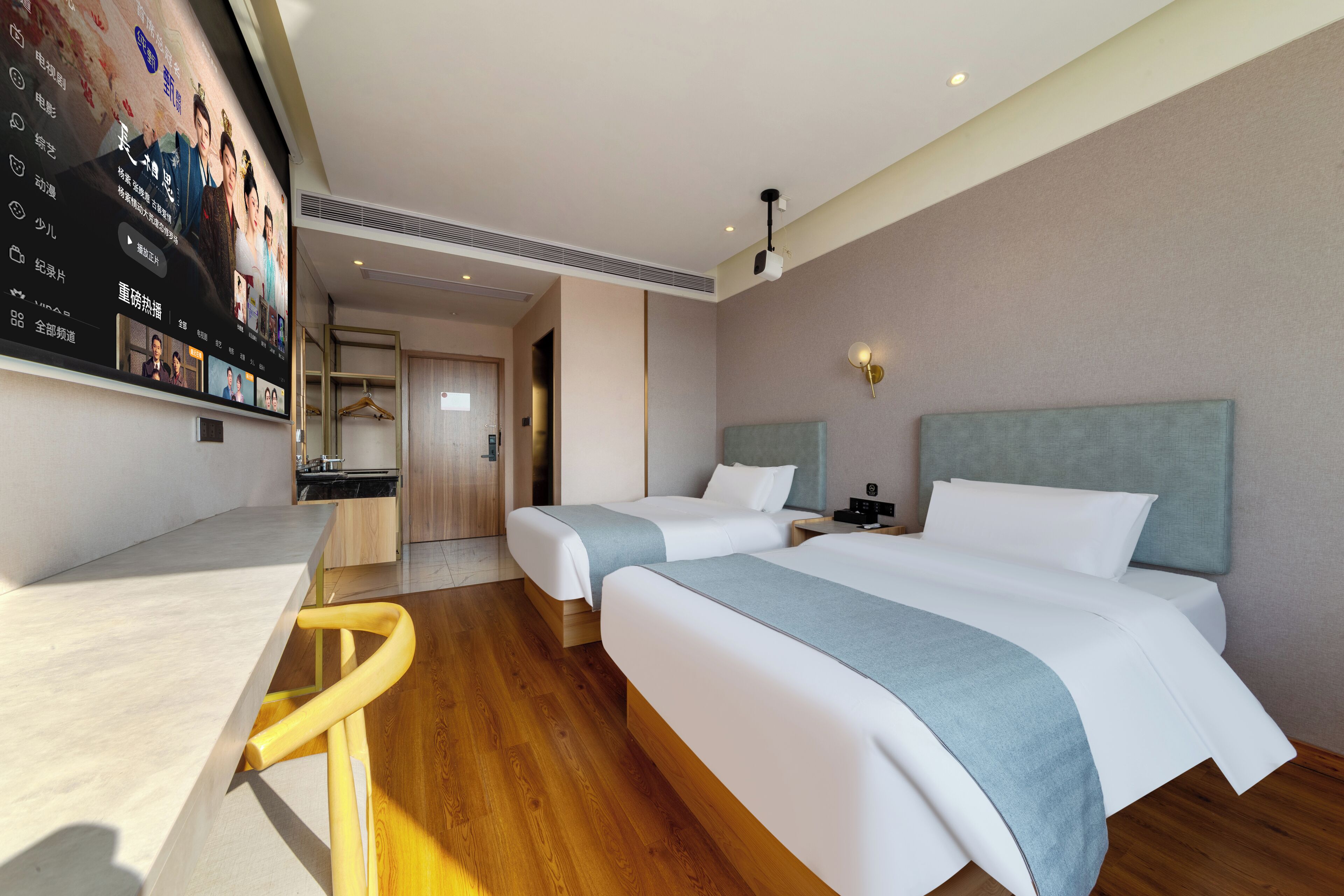 Une chambre d’hôtel avec deux lits, un bureau, un téléviseur fixé au mur et un plancher en bois.