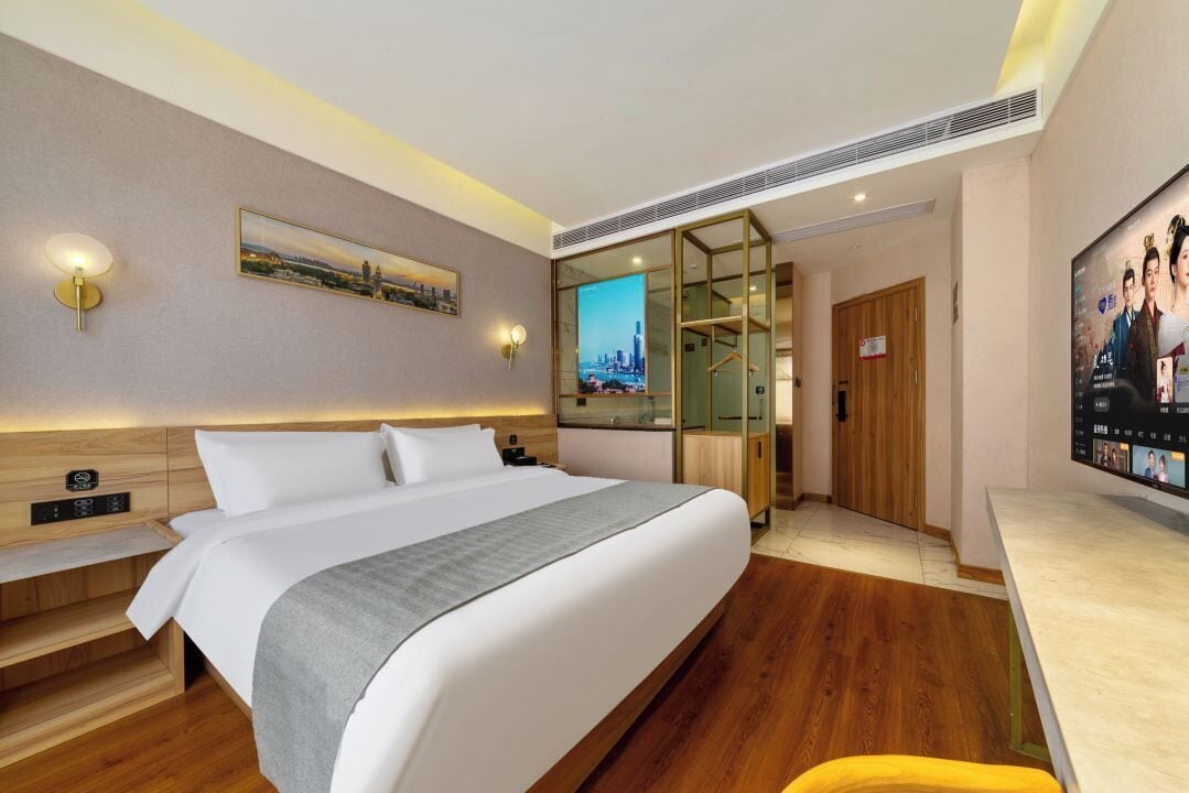 Une chambre d’hôtel moderne, dotée d’un grand lit, d’un bureau et d’une télévision.