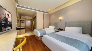 A hotel room with two beds, a desk, a TV, and a bathroom visible through an open door.