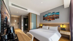 Une chambre d’hôtel avec un grand lit, des tables de chevet, un bureau avec une chaise et un écran de télévision affichant une affiche.