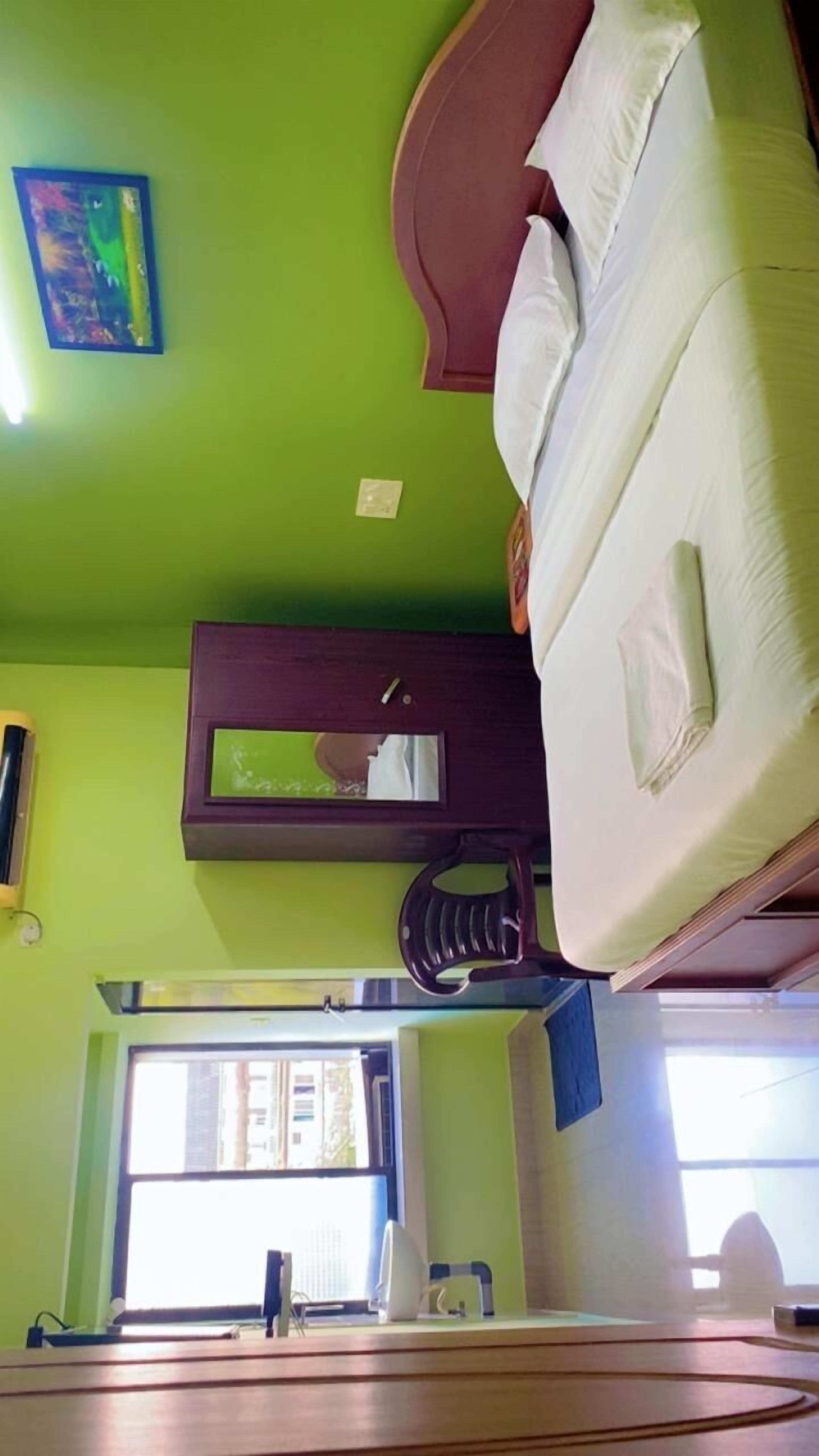 Una stanza con un letto, uno specchio, una finestra e una scrivania con un computer.