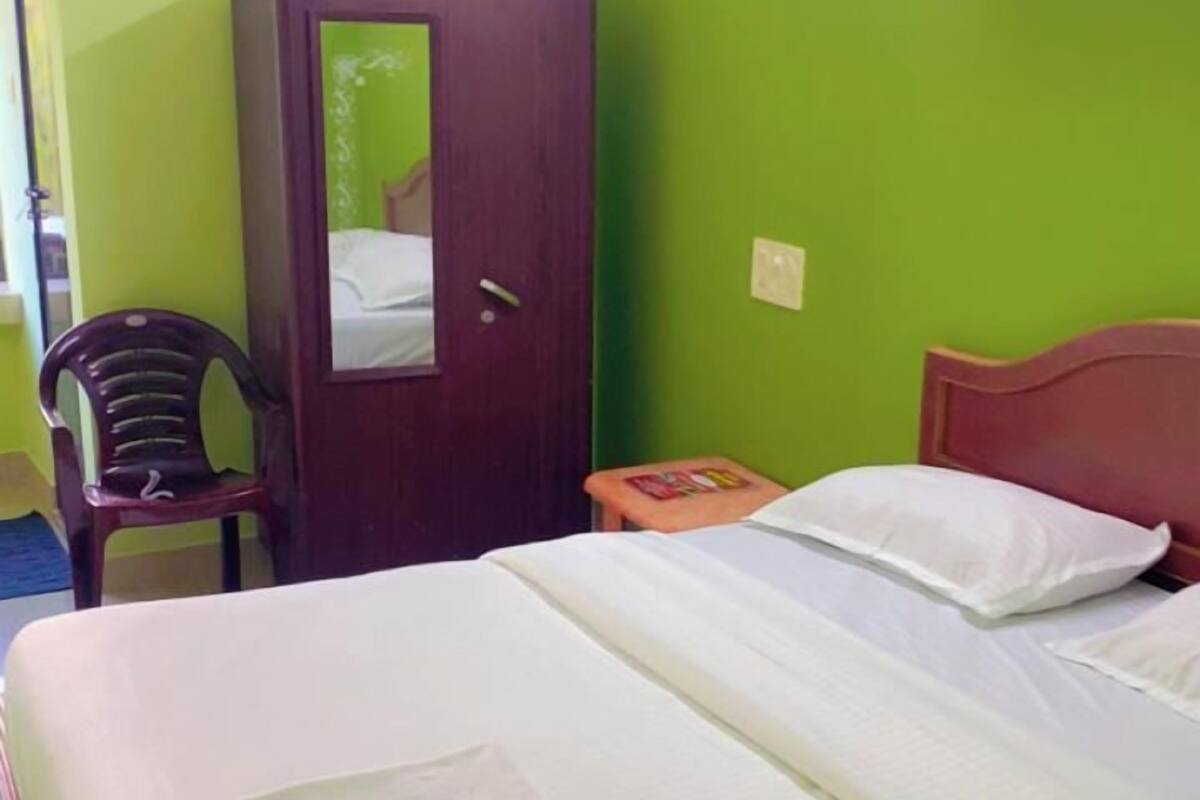 Una habitación con cama, armario, silla y una pequeña mesa.