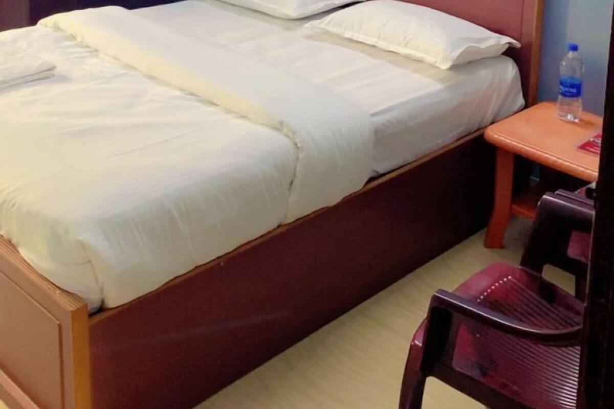 Un dormitorio con una cama de madera, una mesita de noche, una silla, un armario y un cuadro en la pared.