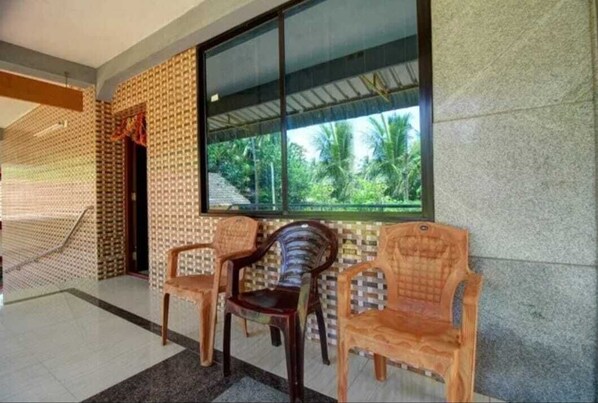 A room with a large window, a patterned wall, and three wooden chairs.