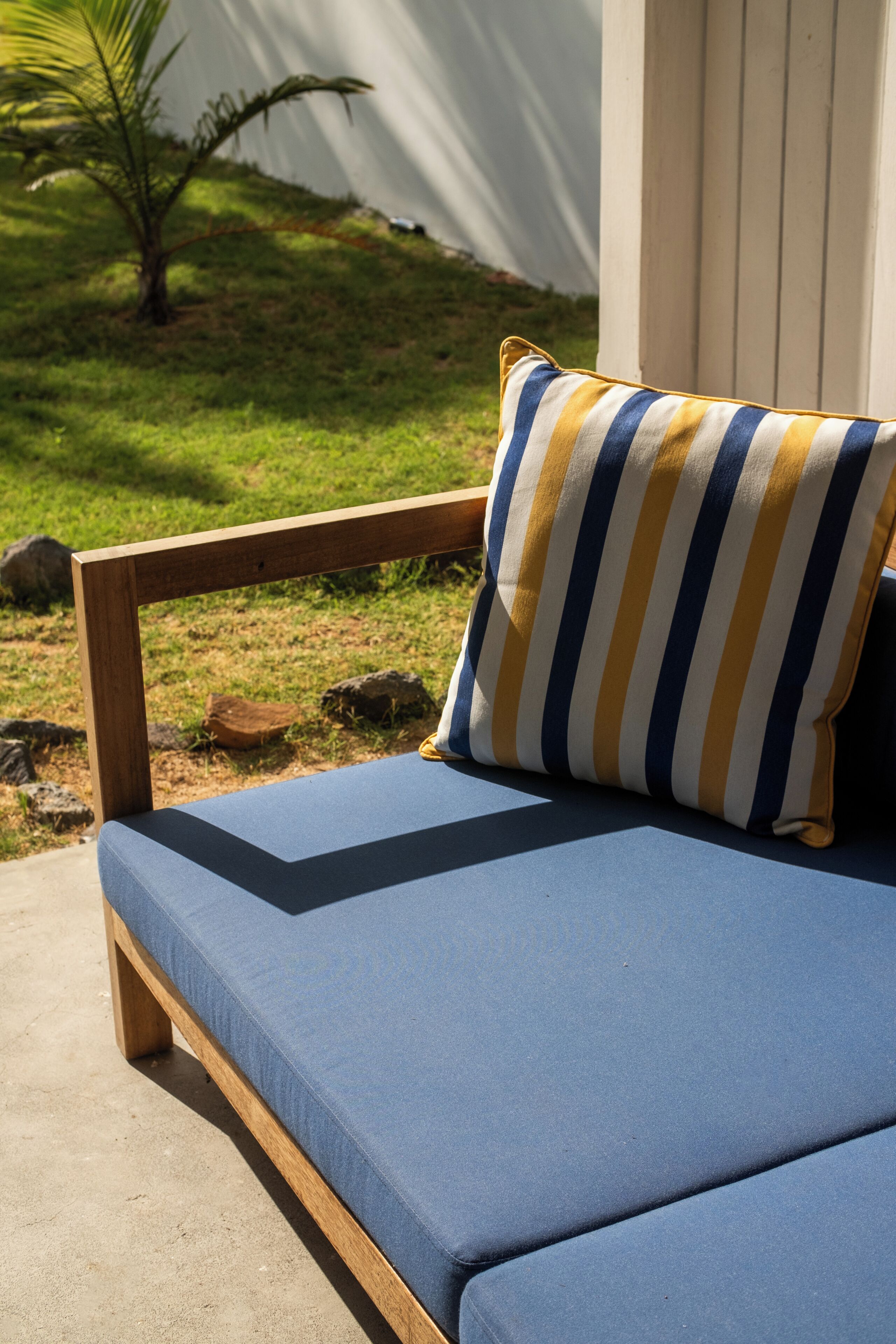Un banco de madera con un cojín azul y una almohada a rayas.