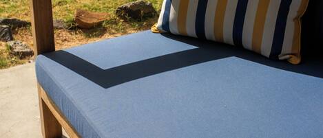 Un banco de madera con un cojín azul y una almohada a rayas.
