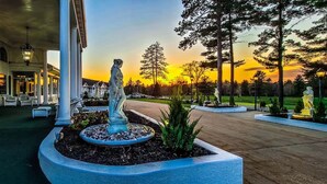 Un imposant bâtiment doté d’un porche, d’une statue au centre et d’un coucher de soleil en arrière-plan.