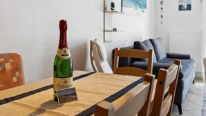Een fles Rötkäppchen champagne op een tafel in een moderne woonkamer met een blauwe bank en een houten eettafel.