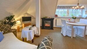 A cozy room with a fireplace, a television, a dining table, and a comfortable seating area.