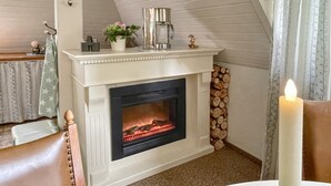 A cozy room with a fireplace, a table, and a chair.