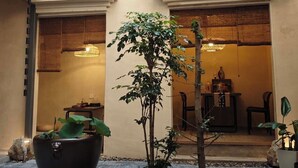 A courtyard with a small tree, a black bathtub, and a dining area with a table and chairs. - NO.9 Alley Yuchen Res Dence (Guilin)