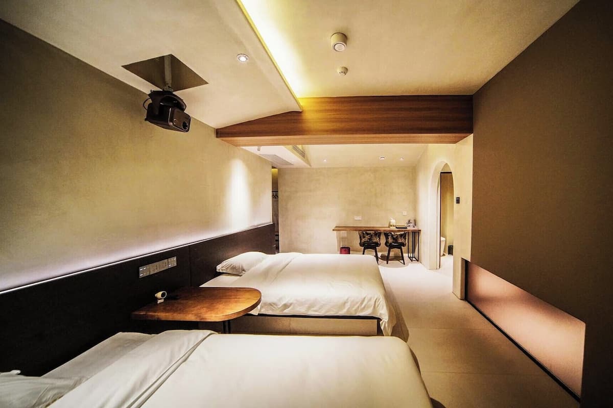 Ein Hotelzimmer mit zwei Betten, einem Schreibtisch und einem Sessel.