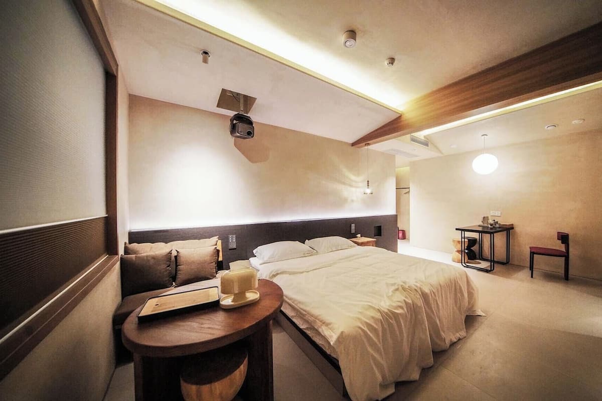 Ein modernes Hotelzimmer mit einem großen Bett, Nachttischen, einem Schreibtisch und einer kleinen Sitzecke.