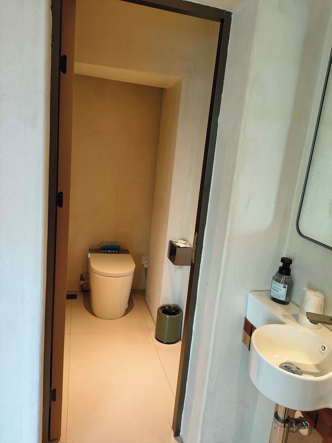Un baño moderno con inodoro, lavabo y espejo.
