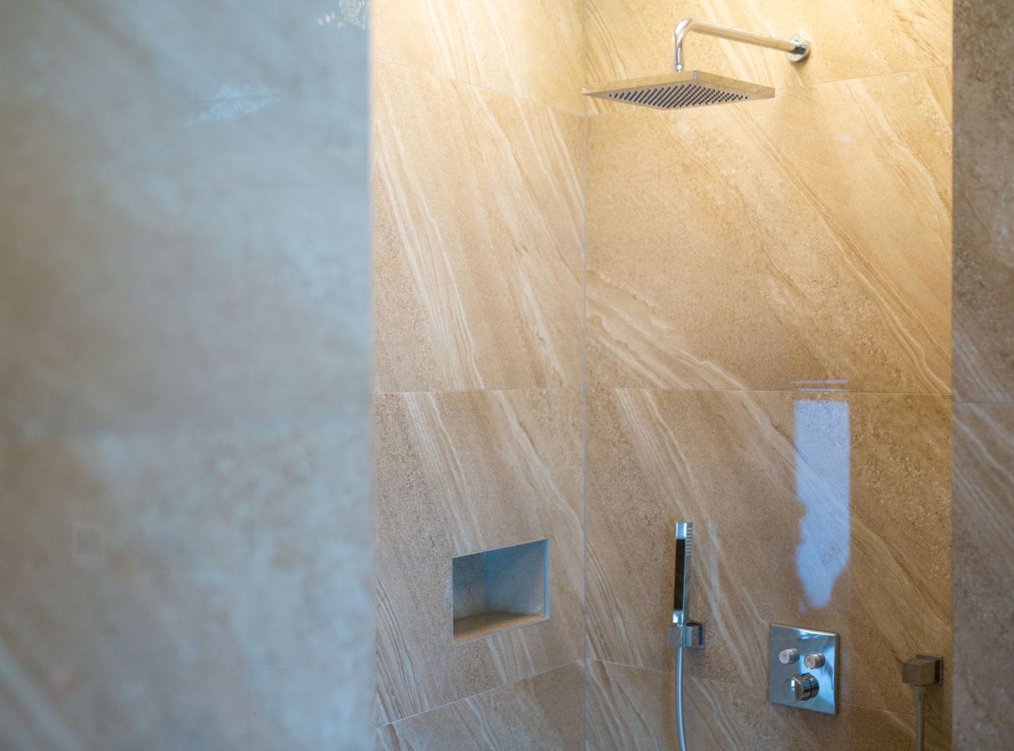A bathroom with a shower, a towel rack, and a wall-mounted control panel.