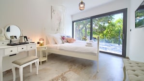 A bedroom with a white bed, a bedside table with a lamp, a dresser, and a bench. - Wellness Apartment Modruna (Vinodol)