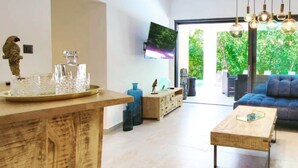 A modern living room with a wooden coffee table, a blue sofa, and a glass-top dining table with decorative items. - Wellness Apartment Modruna (Vinodol)