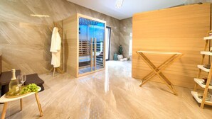 A modern room with a large sliding glass door leading to a balcony, a wooden drying rack, a small table with a bottle and grapes, and a white towel hanging on a rack. - Wellness Apartment Modruna (Vinodol)