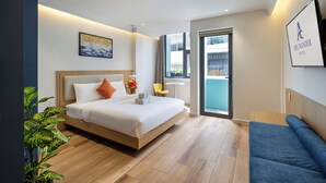 Een moderne hotelkamer met een bed, een blauwe bank, een klein tafeltje en een kamerplant.
