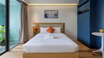 A modern hotel room with a large bed, a bedside table with a vase of flowers, a painting on the wall, and a view through a large window.