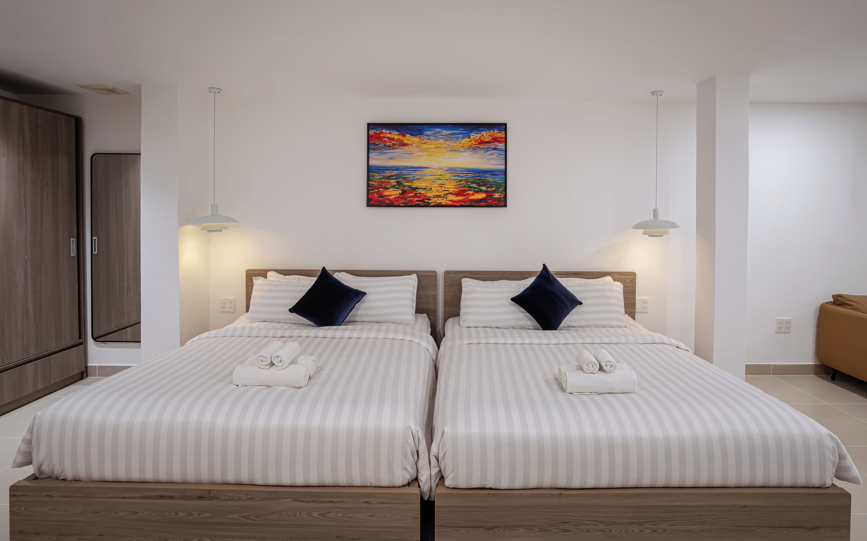 A double bed with striped bedding, two pillows, and a rolled towel.