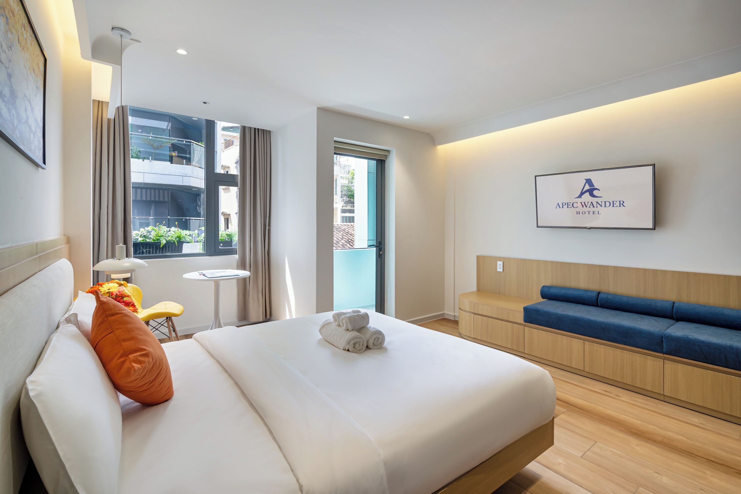 Une chambre d’hôtel avec un lit, une petite table, une chaise, un canapé et une vue sur l’extérieur.