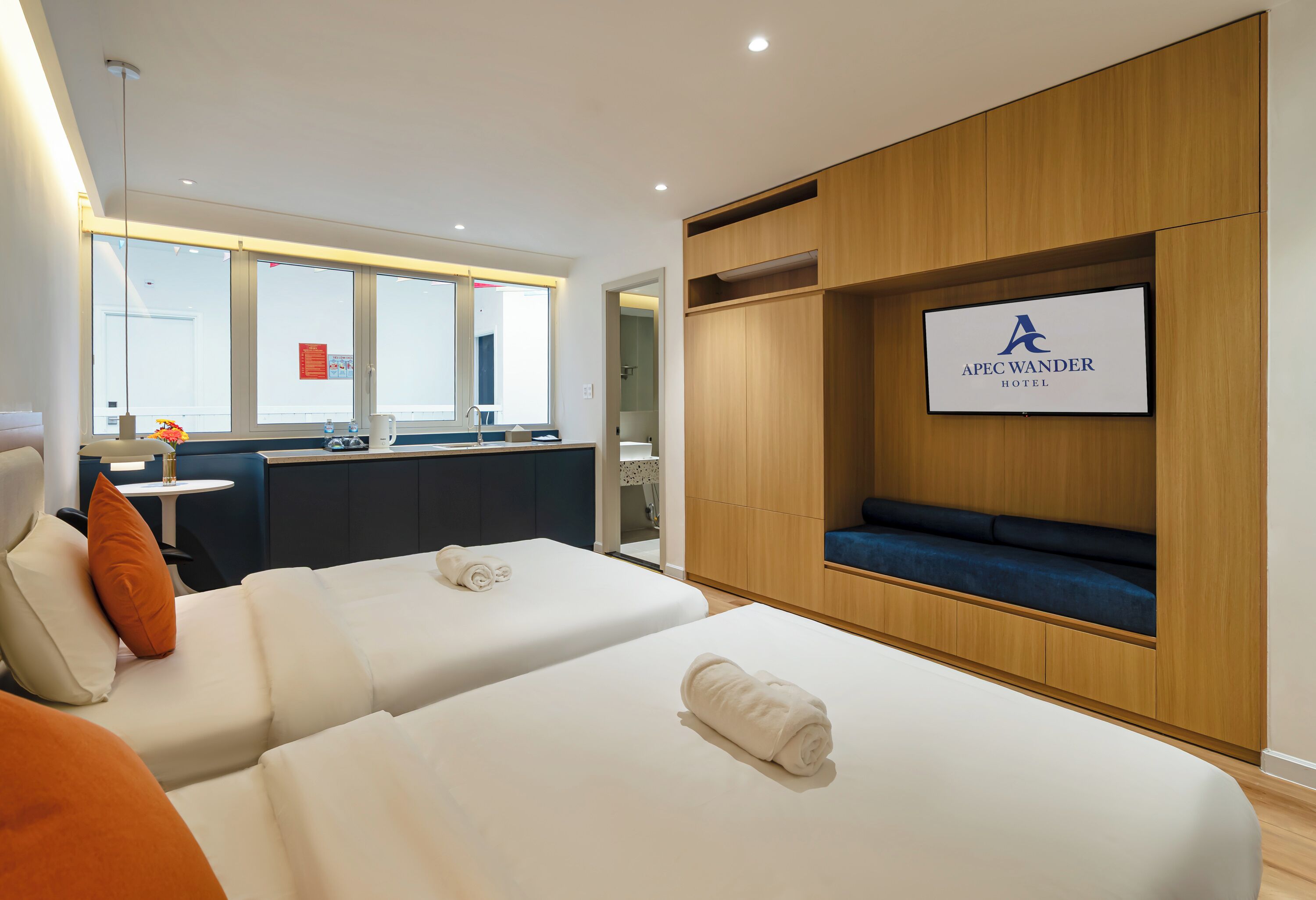 A hotel room with two beds, a seating area, a television, and a view of the outside.