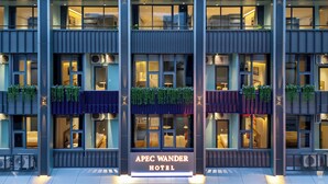 Een modern hotel met een opvallend bord waarop 'APEC WANDER HOTEL' staat.