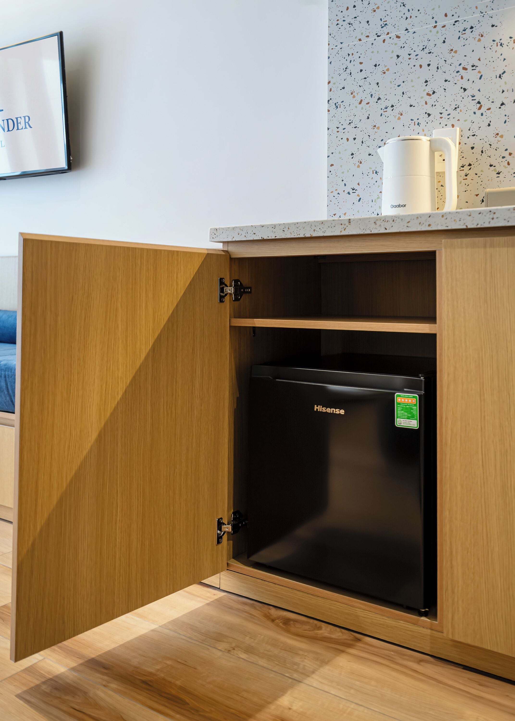 A wooden cabinet with a black Hisense refrigerator inside.