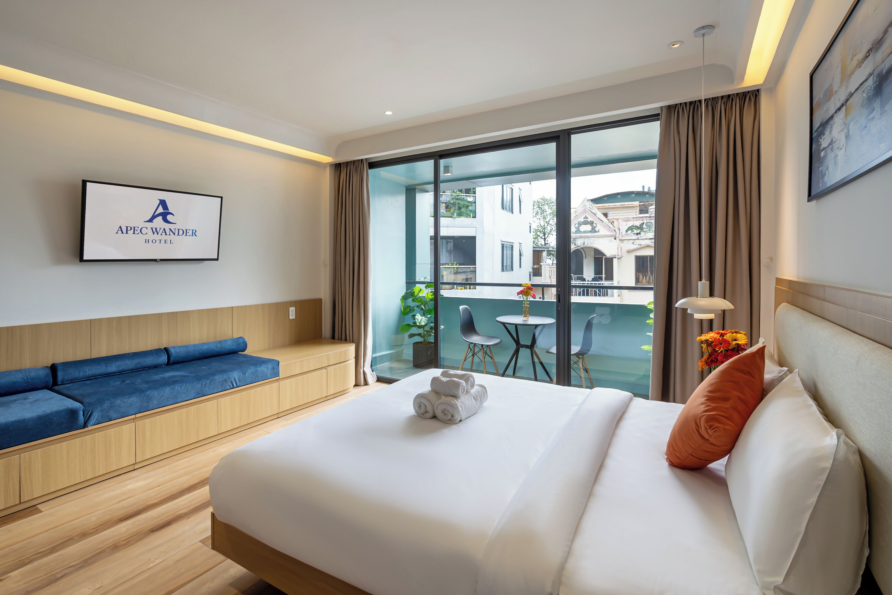 A hotel room with a bed, a blue sofa, a small table, and a view of the city.