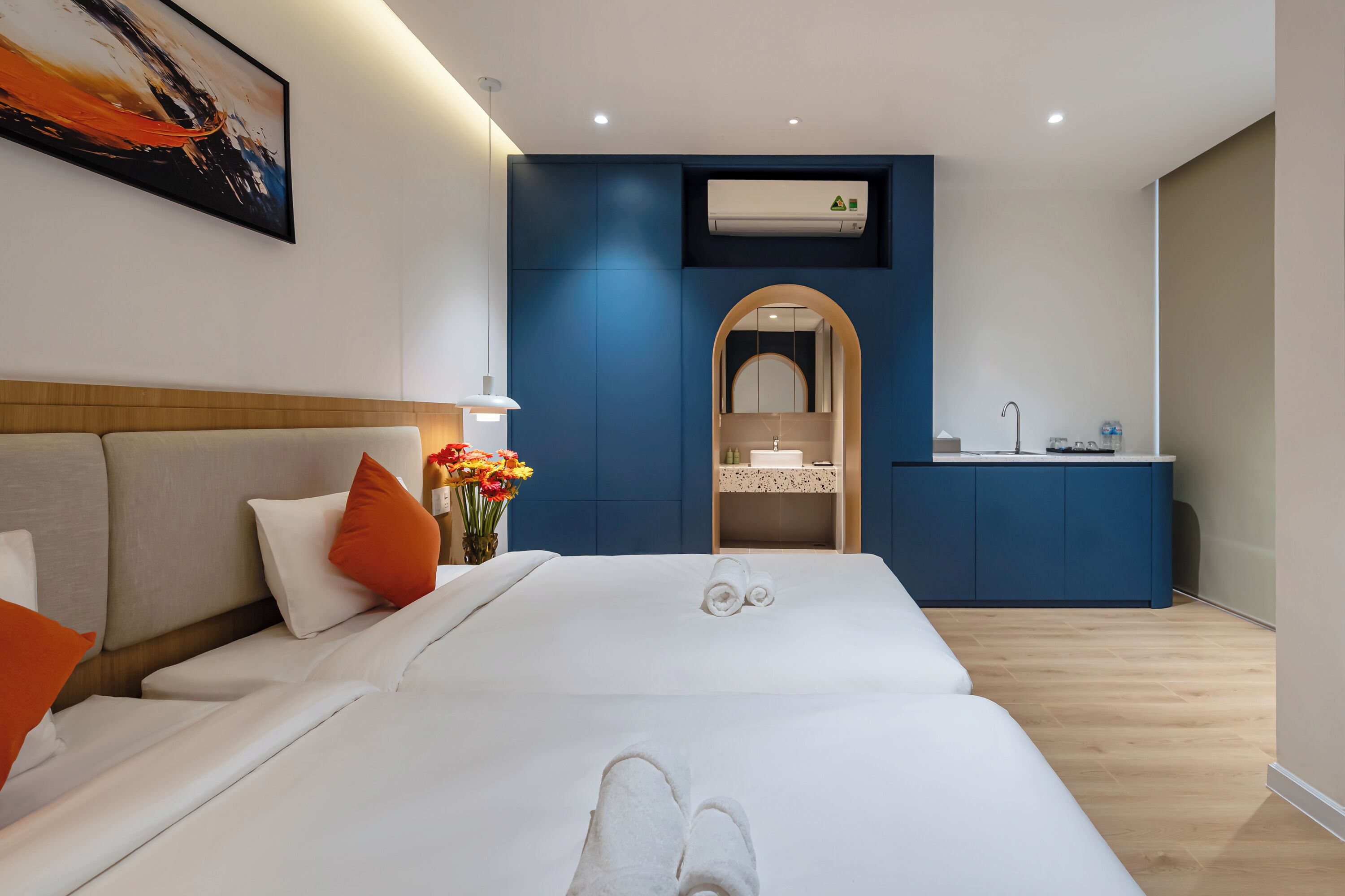A modern hotel room with a large bed, a small kitchenette, and a bathroom.