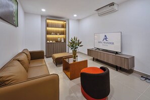 A modern living room with a sofa, ottoman, coffee table, and a flat-screen TV. - APEC WANDER HOTEL - NEAR TAN DINH MARKET (Ho Chi Minh City)