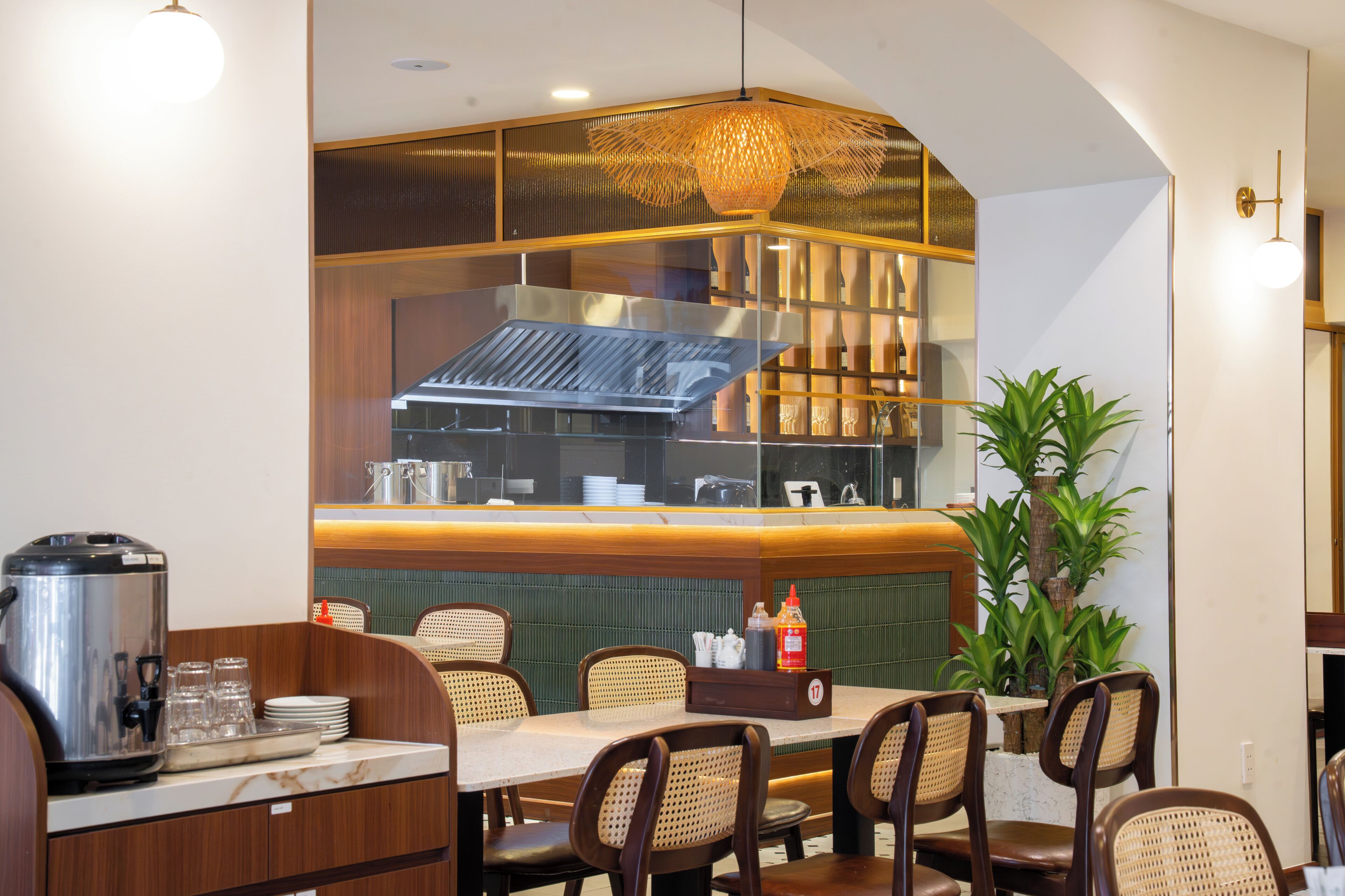 A restaurant interior with a counter, seating, and a decorative plant.