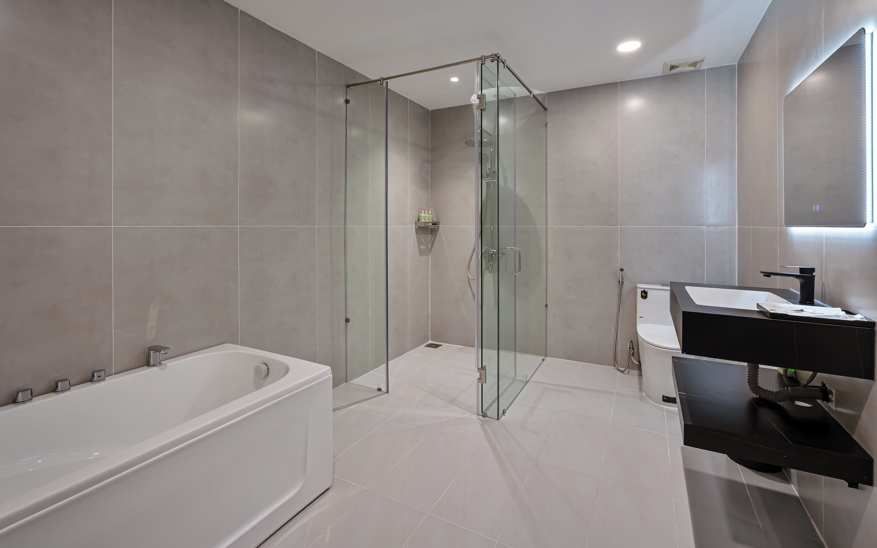A modern bathroom with a glass-enclosed shower, a white bathtub, and a black vanity with a mirror.