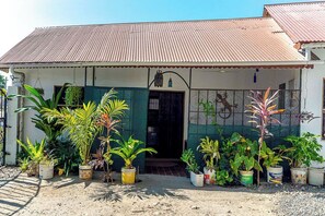 Ein Haus mit Wellblechdach, einer Haustür und einer kleinen Veranda mit Blumentöpfen.