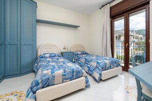 Een slaapkamer met twee bedden, een nachtkastje, een dressoir en een balkon met uitzicht.